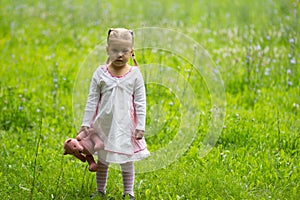 Sad alone child with toy standing in the summer park