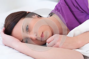 Sad and alone woman lying in her bed