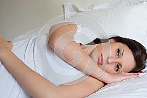 Sad and alone woman lying in her bed