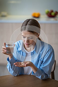 Sad alone woman suffering depression taking antidepressants neuroleptics drinking water feeling bad