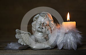 Sad angel with burning candle for bereavement or mourning background photo
