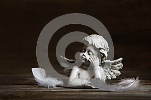 Sad angel with white feathers on a dark background for bereavement. photo