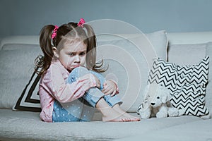 Sad or angry little girl, victim, holding toy dog.