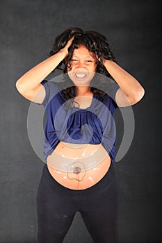 Sad or angry pregnant woman with drawing of sperms reaching egg on belly