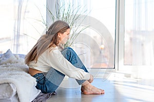 Sad and angry Sad and angry teenage girl sitting on the floor in the room