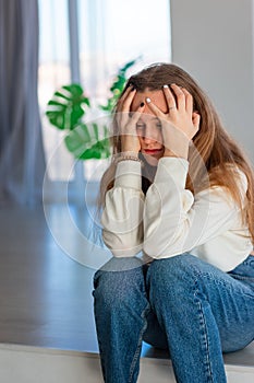 Sad and angry Sad and angry teenage girl sitting on the floor in the room