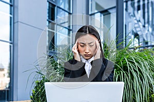 Sad and anxious Asian student, received disappointing news about entering university and college, sitting on a bench with a laptop