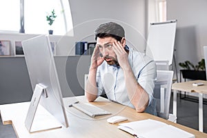 Sad and anxious man working in the office, businessman frustrated by the result of work tired and depressed looking at the monitor