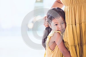 Sad asian child girl hugging her mother leg