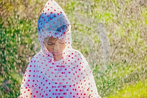 Sad asian child girl wearing raincoat standing under the rain