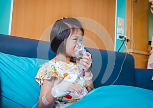 Sad asian child holds a mask vapor inhaler for treatment of asthma. Breathing through a steam nebulizer.