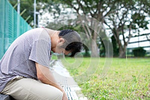 Sad Asian Chinese Man with head down seated on ground