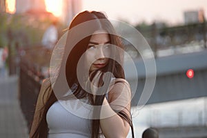 Sad asian girl posing in sunset time on embankment looking away, copyspace