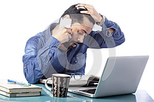 Sad asian man talking on mobile phone and feeling tensed while working on computer keeping hands on head
