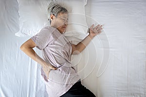 Sad asian senior woman touching hip on her bed,problem of pain while sleep feel backache discomfort,female old elderly suffering