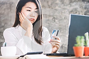 Sad Asian woman having problem with limit credit card for online shopping