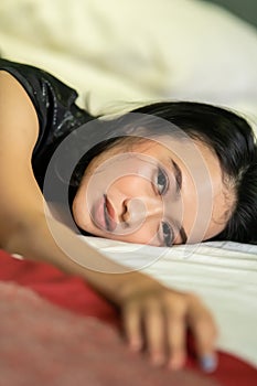 Sad Asian woman sleeping on a white bed while she wearing a black dress with makeup