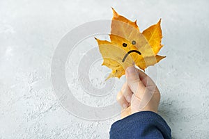 Sad autumn leaf in a children`s hands.