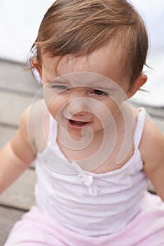 Sad baby, face and sitting outside of curious toddler, little girl or disappointed on outdoor porch. Closeup of young