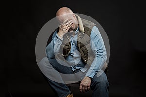 Sad bald man in jeans on a black background. Vertical. Unemployment and financial problems in the global crisis during the