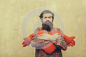 Sad bearded man hugging red heart shape toy with hands