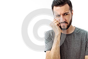 Sad bearded young man standing and having toothache on white background