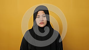 Sad beautiful Asian muslim woman wearing hijab looking at camera, shook her head, disagreement