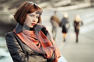 Sad beautiful fashion woman in leather coat walking in city street