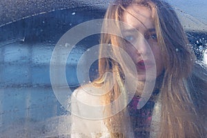 Sad beautiful seksalnaya Pretty sad lonely girl behind wet glass with big sad eyes in a coat