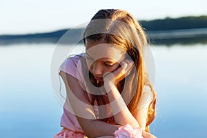 Sad Beautiful teen girl is looking with serious face at seaside