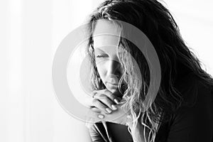 Sad beautiful woman with long curly hairs looking down