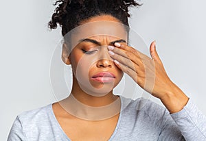 Sad black girl touching her eye, suffering from conjuctivitis