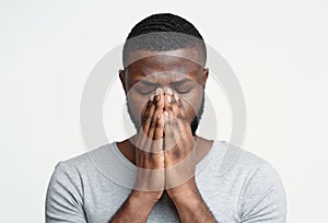 Sad black man holding his nose because sinus pain
