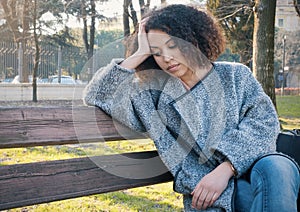 Sad black woman seated alone on a bench