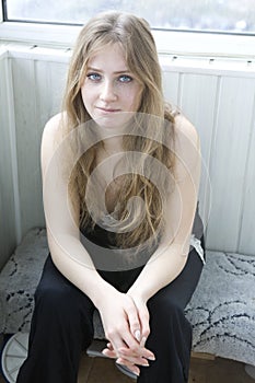 Sad blond teen girl sitting on balcony