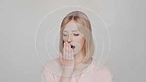 Sad and bored young woman over grey background.