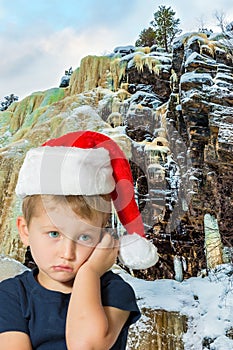 Sad boy with blue eyes in Santa Claus hat