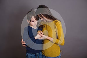 Sad boy with bruised eye, hugging mom and teddy bear at home