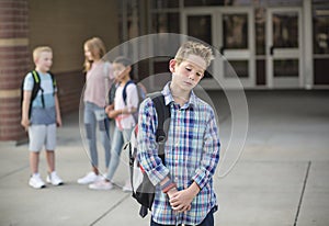 Sad boy feeling left out, teased and bullied by his classmates photo