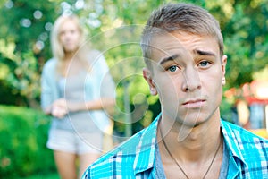 Sad boy with his girlfriend on the background