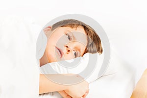 Sad boy laying in bed on white background