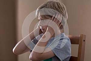 Sad boy plugging ears
