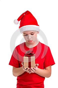 Sad boy, santa hat on his head, with the small gift box in the hands. Concept: christmas or Happy New Year holiday