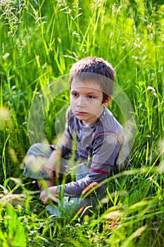 Sad boy sitting in grass