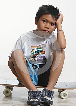 Sad boy sitting on his skateboard