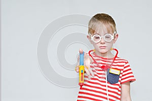 Sad boy with a toy syringe in glasses