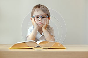 sad boy 3 year old with an open book in front of him, dislexia concept, tired young boy in shirt with a big book photo