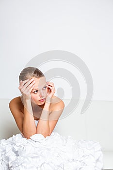 Sad bride crying sitting on a sofa, smitten, pondering photo