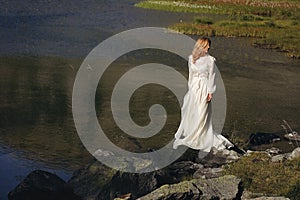 Sad bride posing in a mountain lake
