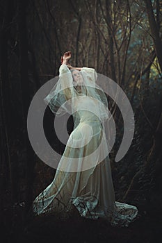 Sad bride with veil in the forest